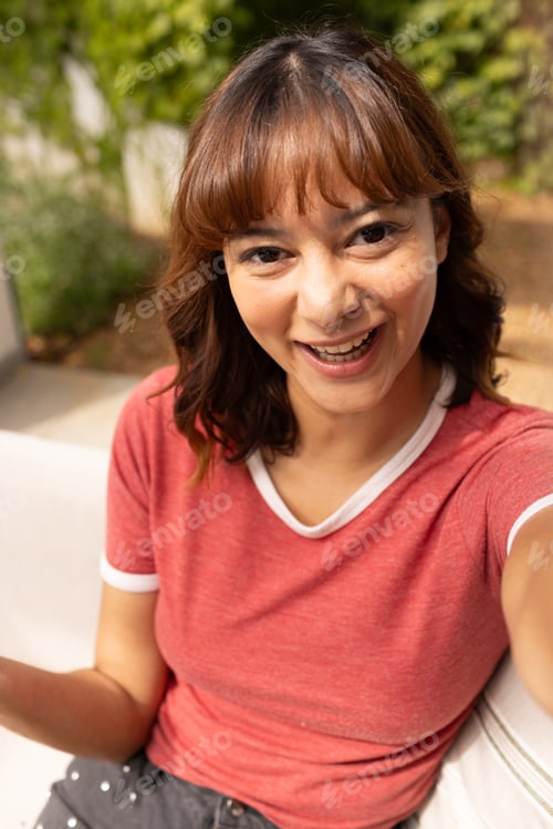 Preview: Young biracial woman smiles brightly outdoors on a video call