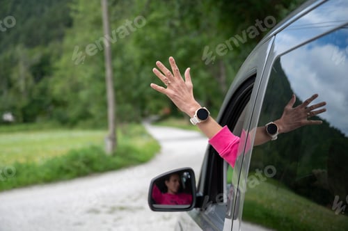 Preview: Female hand sticking out of a window of a driving car