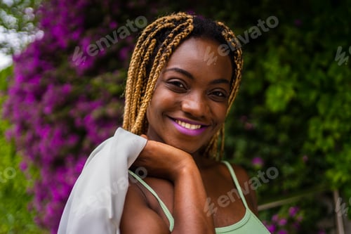 Preview: African woman smiling to the camera while posing on a garden