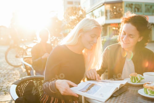 Preview: Happy teenage friends studying on table at sidewalk cafe