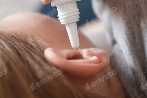 Preview: Mother dripping medication into daughter's ear on blurred background, closeup