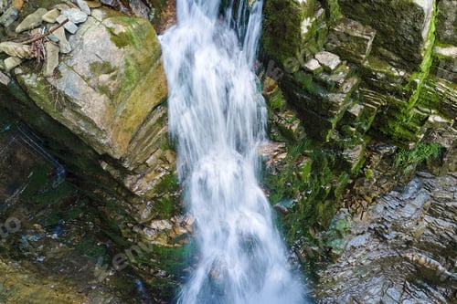 Preview: Amazing landscape of beautiful waterfall on mountain river with white foamy water falling down from
