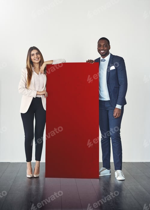 Preview: Studio shot of a young businessman and businesswoman standing next to a blank red placard