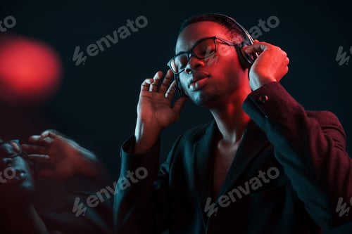 Preview: In glasses. Futuristic neon lighting. Young african american man in the studio