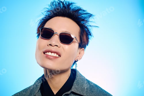 Preview: Stylish young asian man enjoys a moment of confidence against a vibrant blue background