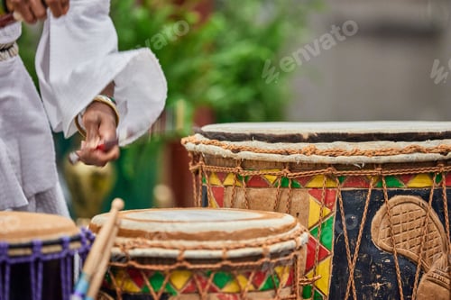 Preview: African drummer holding drumsticks and playing on the park on a sunny day