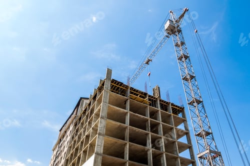 Preview: Modern building under construction against blue sky. Tower crane construction work site