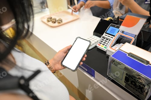 Preview: Female customer preparing to pay with a smartphone at a register
