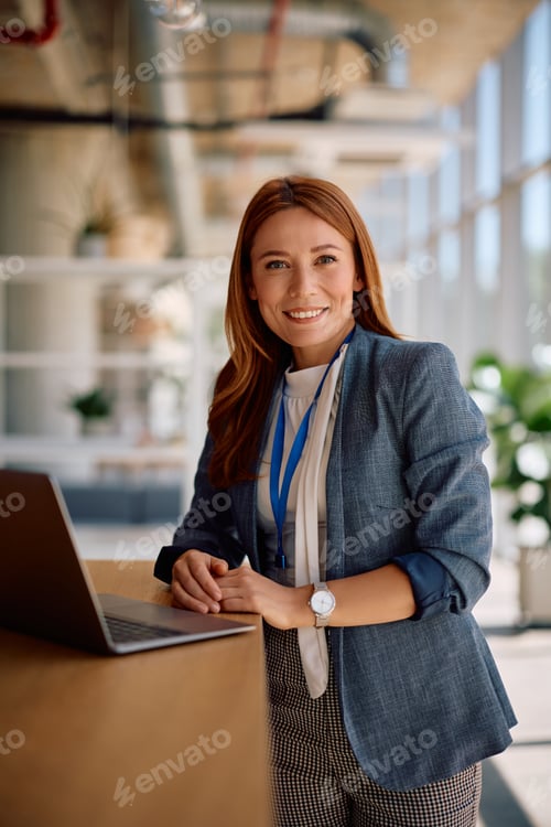 Preview: Happy businesswoman working on a computer and looking at camera.