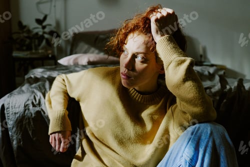 Preview: Woman Sitting on Bed with Hand in Curly Hair