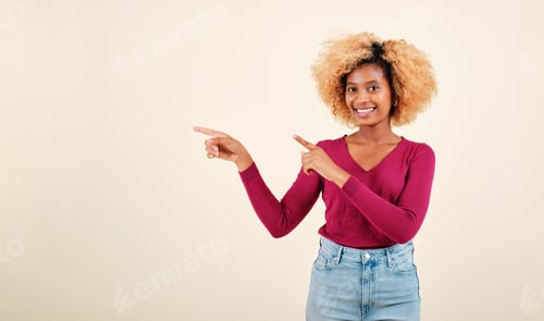 Preview: Happy afro woman pointing to the side to present o promote something while standing