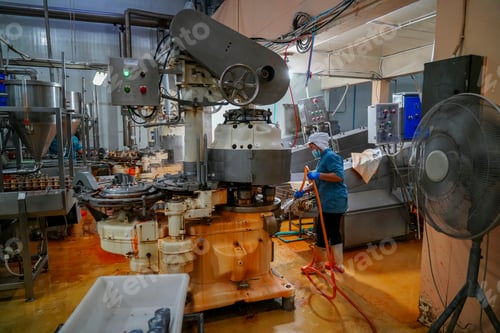 Preview: Worker cleans machinery in active food production facility during daytime hours