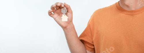 Preview: Banner of young man with the new home keys. Keychain in the shape of a wooden house.