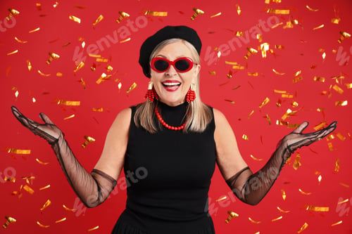 Preview: Happy senior woman in elegant outfit and flying confetti against red background
