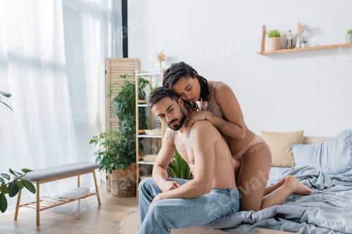 Preview: young and sexy african american woman in lingerie embracing shirtless tattooed man in jeans