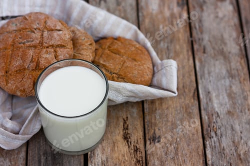 Preview: Fresh organic milk in glass and bottle on rustic wooden table on nature background.