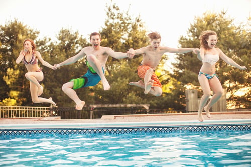 Preview: Friends jumping into a swimming pool on a sunny day