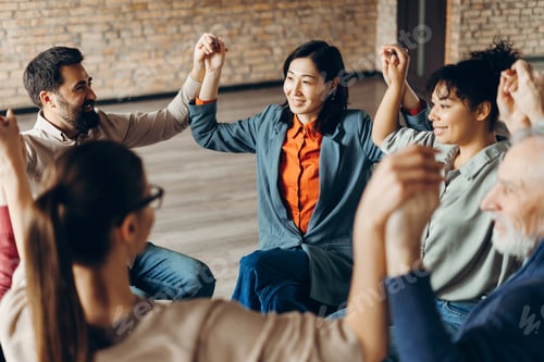 Preview: Diverse group of smiling coworkers holding hands during corporate teambuilding activity