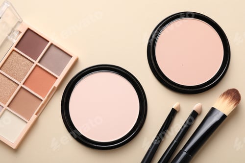 Preview: Eyeshadow palette, face powders and makeup brushes on beige background, flat lay