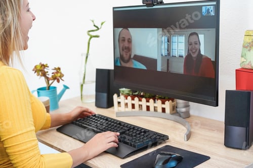 Preview: Cheerful young woman having video call on computer with friends - Focus on