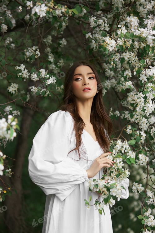 Vista previa: Portrait of a woman in the branches of a blooming apple tree. Beautiful natural makeup