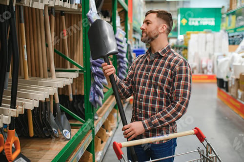 Preview: Portrait of a happy man holding shovel in hardware store