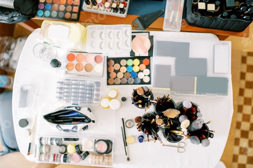 Preview: Large table with sets of cosmetics and makeup brushes. Top view