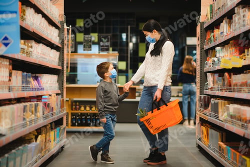Preview: Young woman and her little son wearing protective face mask shop a food at a supermarket