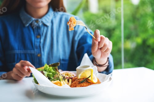 Preview: Closeup image of a beautiful asian woman eating fish and chips on table in the restaurant