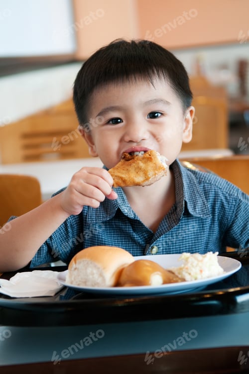 Visualização: Portrait of a young Asian boy eating fried chicken drumstick