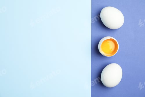 Preview: Chicken eggs with half yolk on two tone background, space for text
