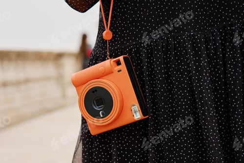 Preview: Female traveler holding vintage instant camera