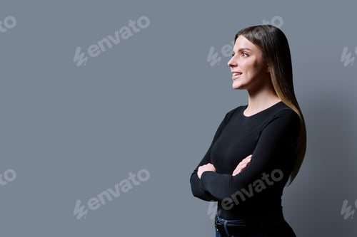 Preview: Profile view of young confident woman on gray studio background, copy space