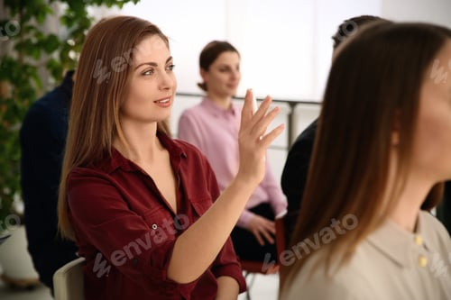 Preview: Woman raising hand to ask question at business training indoors
