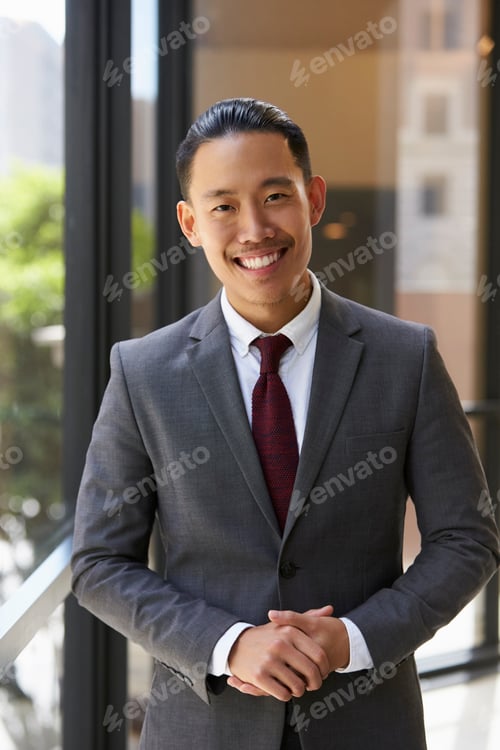 Preview: Young Asian businessman smiling to camera, vertical