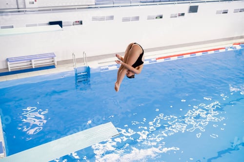 Preview: the olympic sport, sports diving in the swimming pool, female athlete doing spin in the air
