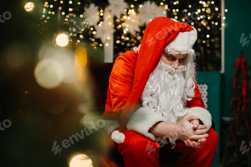 Preview: Sad santa claus sitting and thinking near christmas tree