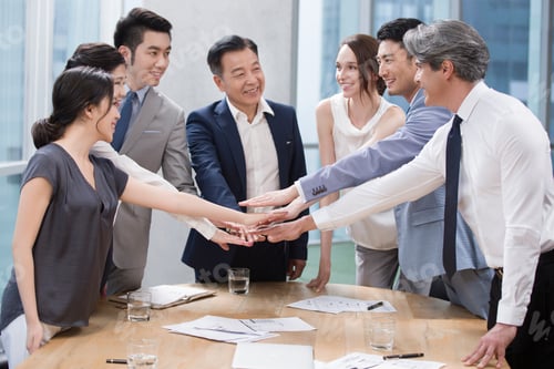 Preview: Confident business people stacking hands in meeting room
