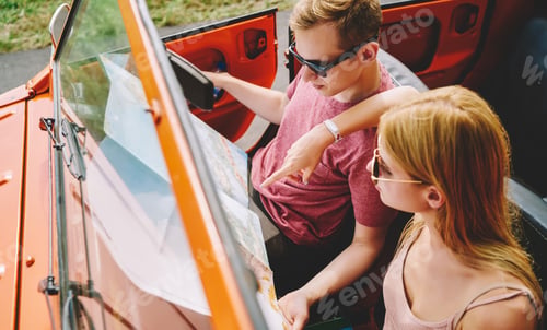 Preview: Happy couple sitting in car and choosing route on map