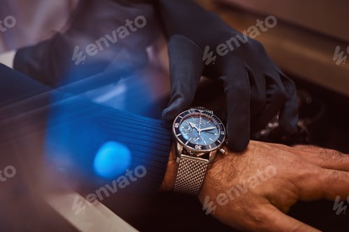 Preview: Assistant helps the client to try on exclusive men's watches, close-up hands.