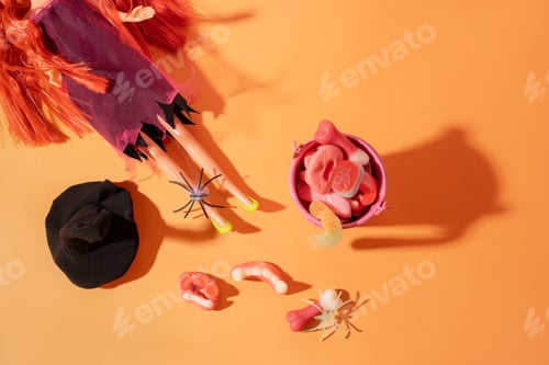 Preview: Doll with red hair in a witch costume next to a pink bucket filled with candy