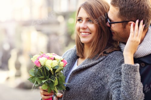 Preview: Young couple with flowers kissing in the city