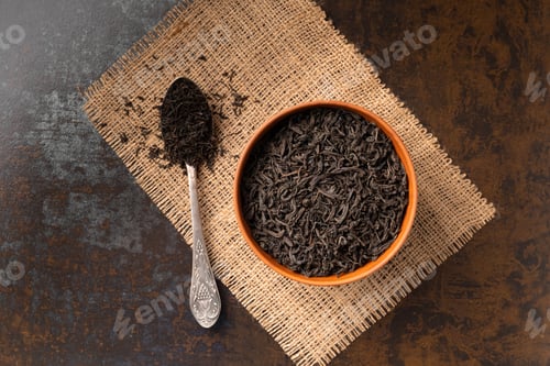 Preview: Dry black tea in a bowl and a spoon on a dark background