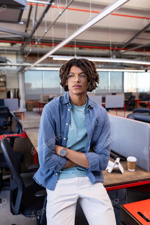 Preview: Confident man in modern office wearing casual attire, standing with arms crossed