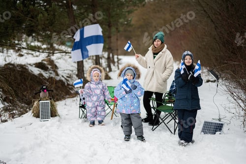 Preview: Finnish mother and children with Finland flags on a nice winter day. Nordic Scandinavian people.