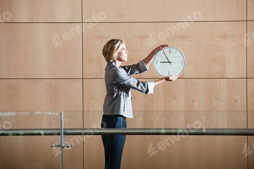 Preview: Businesswoman holding clock