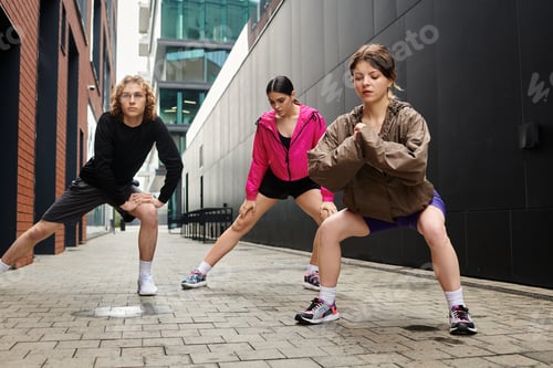 Preview: Sporty young trio engaged in outdoor stretching routine in urban setting