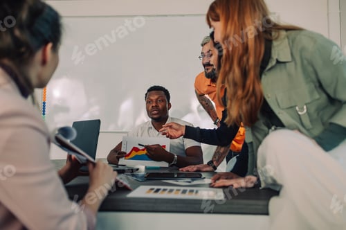 Preview: African american businessman showing charts to his colleagues during a meeting