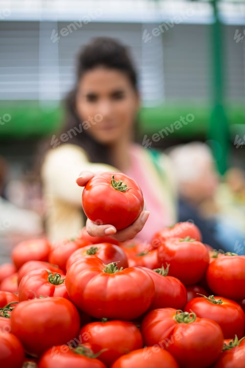 Preview: Pretty young woman buying vegetables on the market