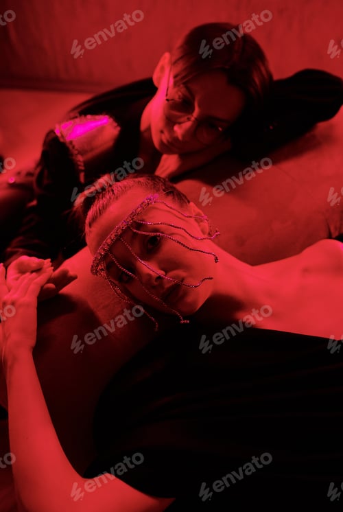 Preview: Teenage couple in posh apparel relaxing by armchair in studio or night club